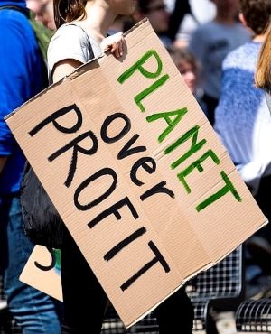 woman holding planet over profit placard